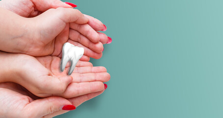 Woman hands holding white tooth isolated on pastel blue background. Teeth care and protection concept. Closeup