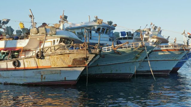 Fishing boats swaying on waves. Windy sunny day at seaport. Old yachts, ships floating on water surface in harbor. Sea town, rest on ocean coast, on river bank, travel, tourism, fishery