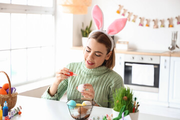 Beautiful woman painting Easter eggs at home