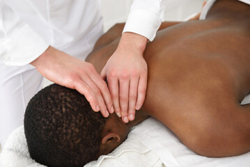 African american man having neck massage in spa, white background. Copy space