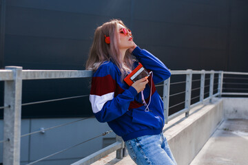 modern retro style 90s, girl in a blue sports jacket, cassette player, listening to music, urban style mood