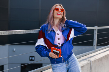 modern retro style 90s, girl in a blue sports jacket, cassette player, listening to music, urban...