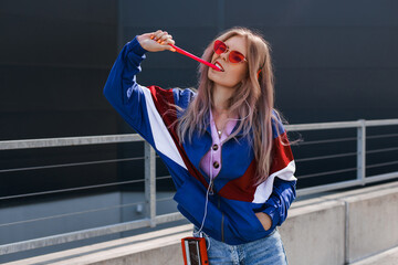 modern retro style 90s, girl in a blue sports jacket, cassette player, listening to music, urban style mood