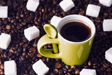 Green mug with black coffee. Pieces of sugar and coffee beans on the table.