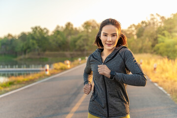 Happy attractive young woman wearing her warm up jacket while running at a local park