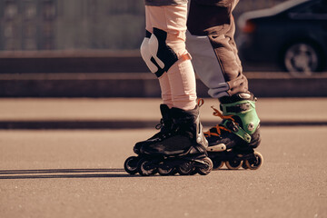 Two roller skaters ride on roller skates next to the road.