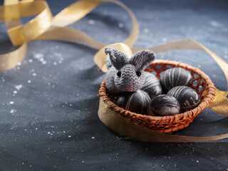 A wicker basket with eggs painted with karkade tea and an Easter bunny toy. Copy space