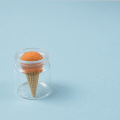Ice cream in a glass jar, on a blue background with copy space. Minimalistic scene.