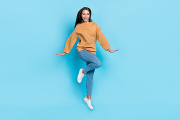 Fototapeta na wymiar Full length photo of cool young brunette lady jump wear sweater jeans shoes isolated on blue background