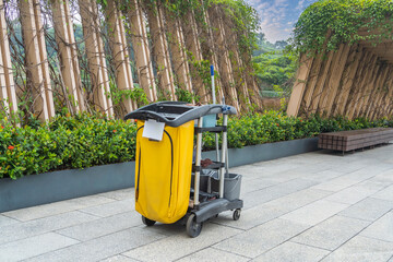 Cleaner cart in a public place with cleaning products: mop, buckets for cleaning the floor, broom scoop, household chemicals, household rags © xiaoliangge
