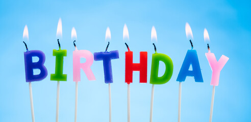 Colorful Candles on a  Blue Background that Spell Birthday