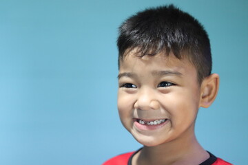 Asian boy with short black hair, with school hairstyle, kindergartener, cute, smiling with happy teeth, seeing face, eyes, nose, eyebrows, ears, neck and broken teeth, does not look at the camera.
