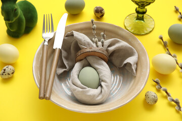 Stylish table setting for Easter celebration on yellow background