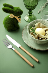 Stylish table setting for Easter celebration on green background