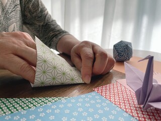 折り紙を折る高齢女性の手