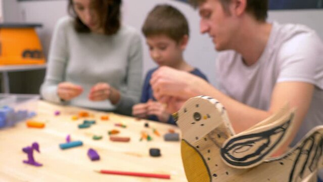 Mom, Dad and son play with clay. Together they use their imagination to create objects and puppets
