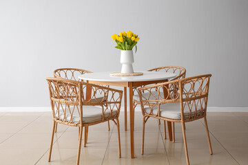 Vase with tulips on dining table in room interior