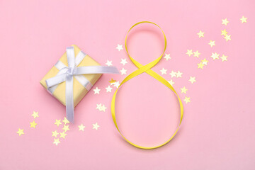 Figure 8 made of ribbon, gift box and confetti on color background. International Women's Day celebration