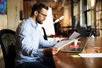 Obraz premium Young businessman using laptop in his office. Handsome man working on the project.