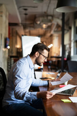 Young businessman using laptop in his office. Handsome man working on the project.