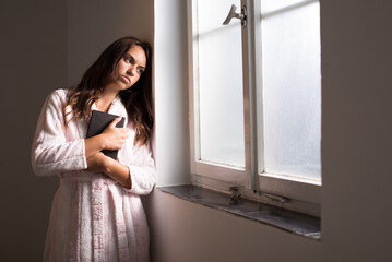 Sick woman in bathrobe looking through hospital window