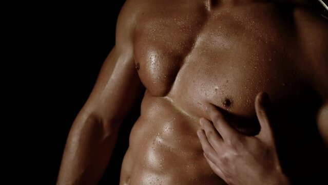 Strong athletic man showing muscular body and six pack abs on black background. Strong athletic man fitness model showing six pack abs. Naked male chest isolated on black background.
