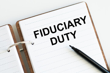 text fiduciary duty on an open notepad on the table, next to it is a black marker