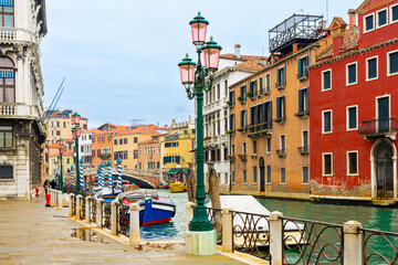A view over Venice street along the narrow canal with floating motorboats.