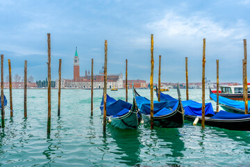 December 2, 2021 - Venice, Italy: Gondolas moored at San Marco Gondola Service Station on Grand Canal with Chiesa di San Giorgio Maggiore on the background.