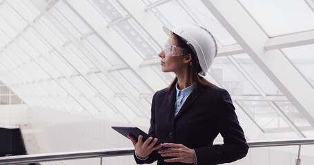 Successful intelligent woman architect standing at new office center using tablet to look at building plan drawing. Female engineer working at construction site.