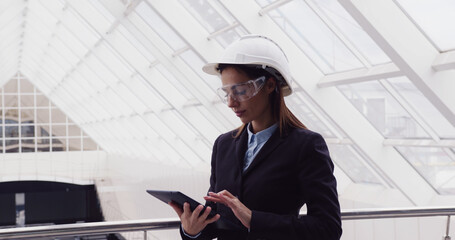 Successful intelligent woman architect standing at new office center using tablet to look at building plan drawing. Female engineer working at construction site.