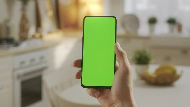 Handheld Camera: Point of View of Man on Kitchen Room Holding Chroma Key Green Screen Smartphone Watching Content Without Touching or Swiping. Boy Using Mobile Phone, Browsing Internet, Watching