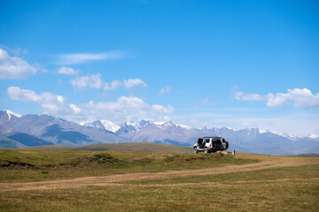 4x4 offroad vehicle with mountains and cloudy sky background. Summer road trip concept.