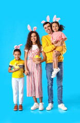 Happy family with Easter rabbit and eggs in basket on blue background