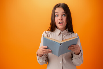 Portrait of clever teen girl with books against orange background