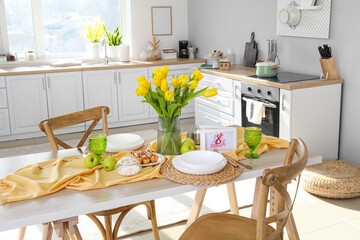 Dining table with setting and beautiful tulips in kitchen interior. International Women's Day celebration