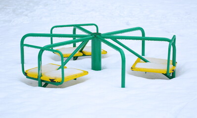 Children's carousel in snow and in drops of melt water