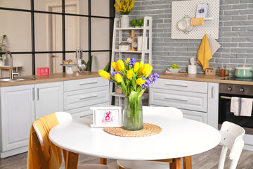 Vase with flowers and greeting card with text 8 MARCH on dining table. International Women's Day celebration