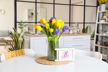 Greeting card with text 8 MARCH and flowers on dining table. International Women's Day celebration