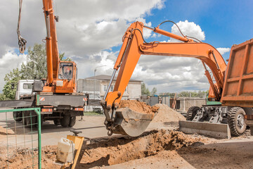 Excavation works. The bucket of the tractor excavator machine loads the soil with a heavy shovel on...