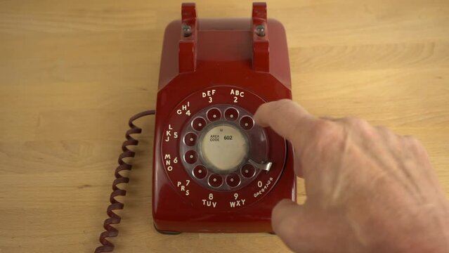 A man dialing 911 on a vintage rotary telephone