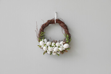Beautiful Easter wreath hanging on grey wall © Pixel-Shot