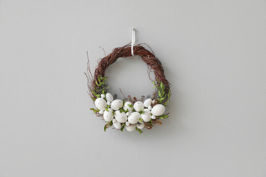 Beautiful Easter wreath hanging on grey wall
