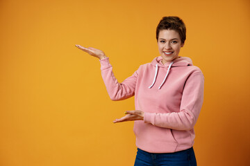 Young woman with short hair over studio color background pointing finger to the side