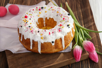 Tasty Easter cake with eggs and flowers on wooden table