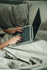 hands and laptop on the bed close-up