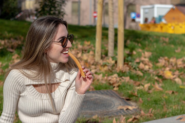 Fototapeta premium Young girl in winter outfit eating churros at a Christmas market