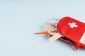 A travel or home first aid kit with a thermometer, pills on a blue background. Banner with space...