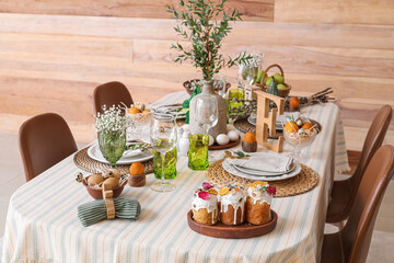 Stylish Easter table setting near wooden wall in room