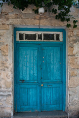 Old blue wooden door in small cypriot village and grape plant